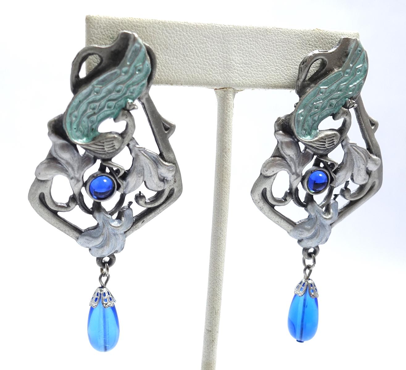 These vintage signed dangling earrings have an intricate designed with leaf type green enameling on silver tone setting with a blue stone dangling at the bottom.  In excellent condition, these clip earrings measure 3” x 1-3/8” and are signed “JJ”.
