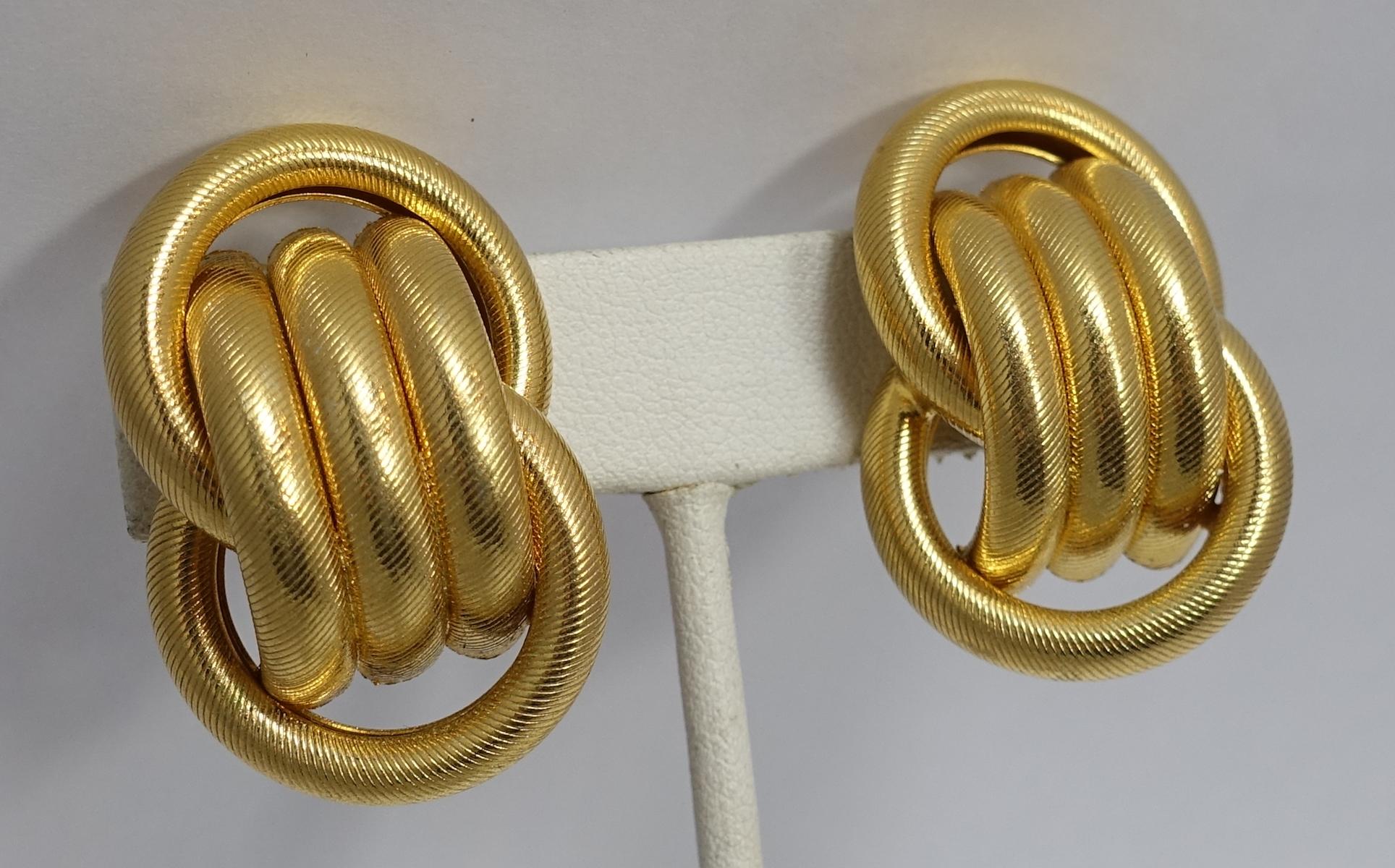 These vintage signed earrings feature a swirling design in a gold tone setting.  These clip earrings measure 1-3/8” x 1” and are signed “Napier”.  They are in excellent condition.