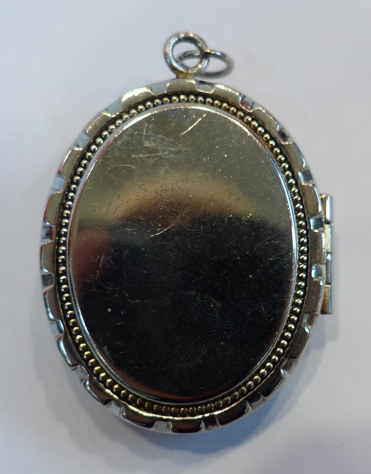 This vintage pendant features a locket with a heavily carved angels design in a silver tone setting.  In excellent condition, this locket pendant measures 1-3/4” x 1-3/8”.