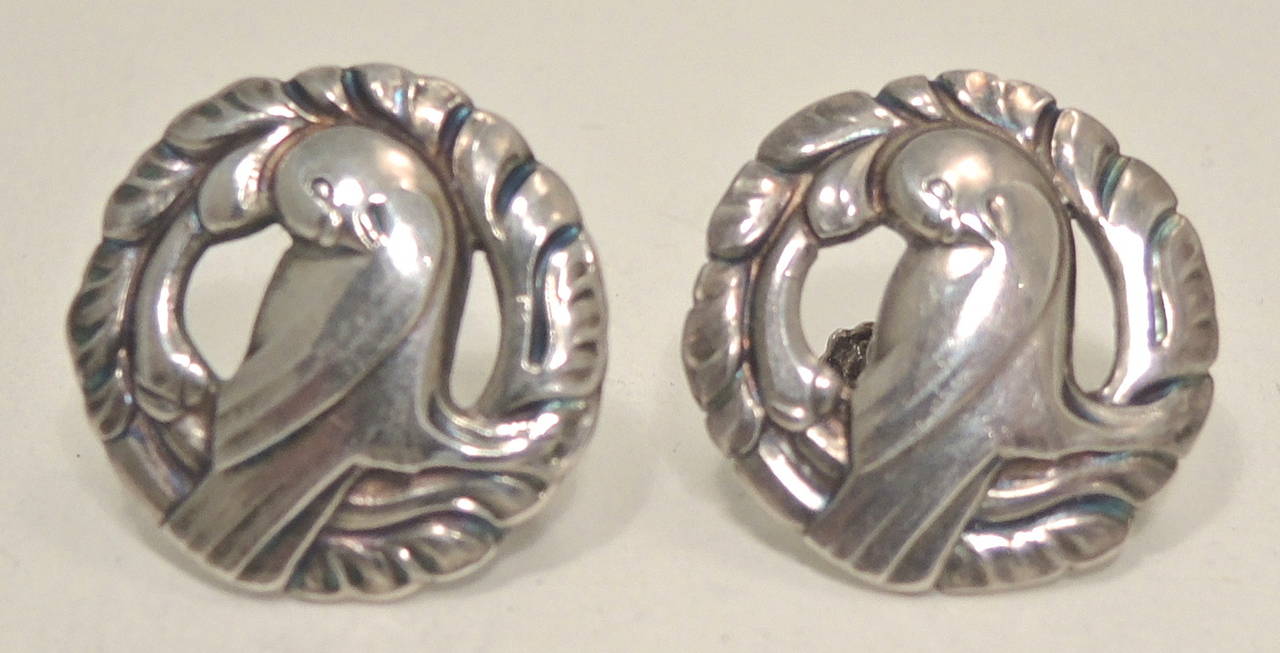 These signed Georg Jensen Denmark earrings feature a heavily carved sterling silver design.  In excellent condition, these screw-on earrings measure 7/8” in diameter and bear the Jensen Hallmark signed “975 Sterling Denmark 66”.