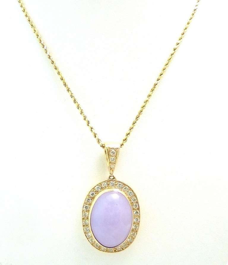 This pendant features a cabochon cut 10ct lavender jade stone with 1.5ct of VS-H diamonds in a 14kt gold setting. In excellent condition, the pendant measures 1 ¾” x 7/8” and the 14kt gold chain is 24” x 1/8” with a spring closure.