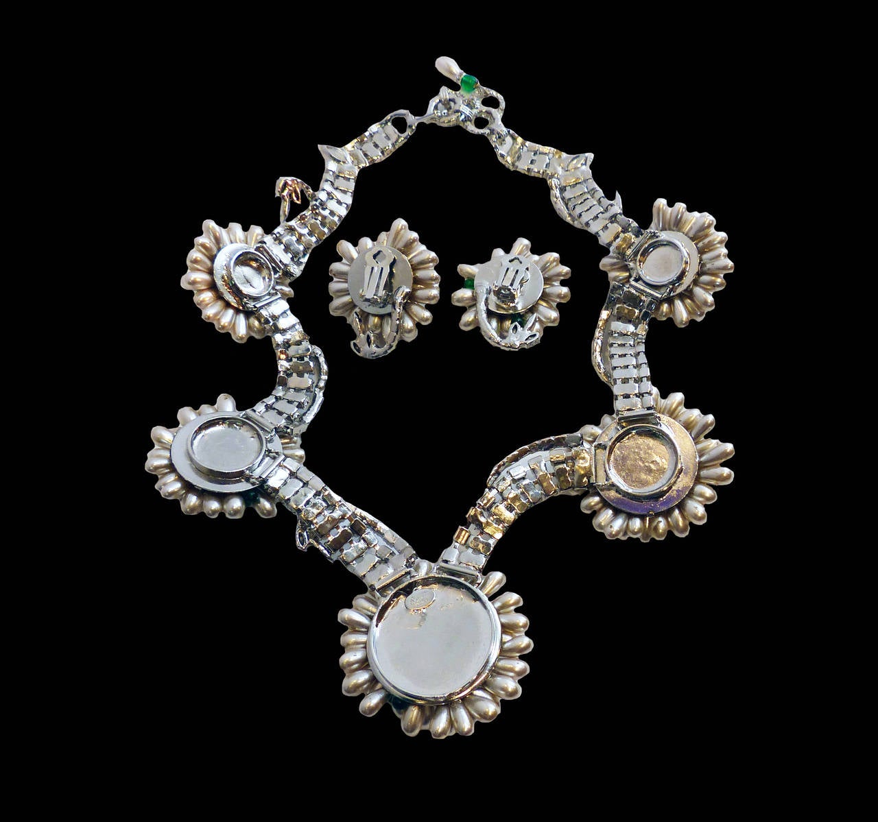This one-of-a-kind set by Robert Sorrell features faux pearls with green glass beads and clear crystals accents in a silver-tone setting.  The necklace measures 17 ½” long with a hook closure; the centerpiece is 2 ¼” in diameter.  The clip earrings