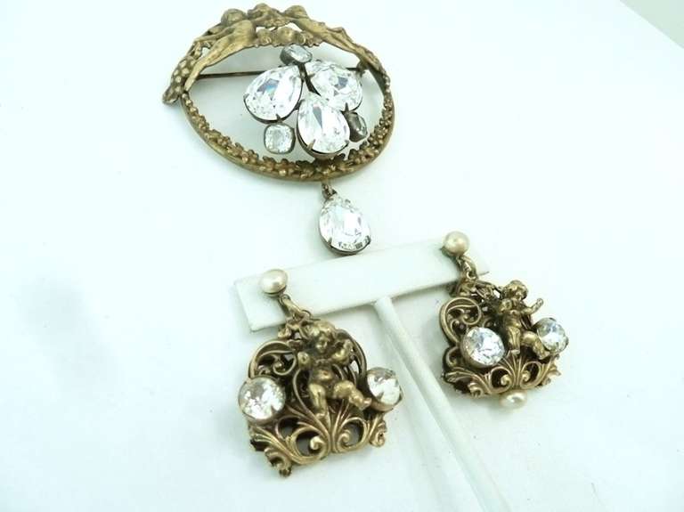 This vintage signed Joseff set features the famous cupids design with clear rhinestone accents in a gold-tone setting. The pin measures 3 5/8” x 2 ¾”; the clip earrings are 1 5/8” x 1 ¼”. In excellent condition, this set is signed Joseff.