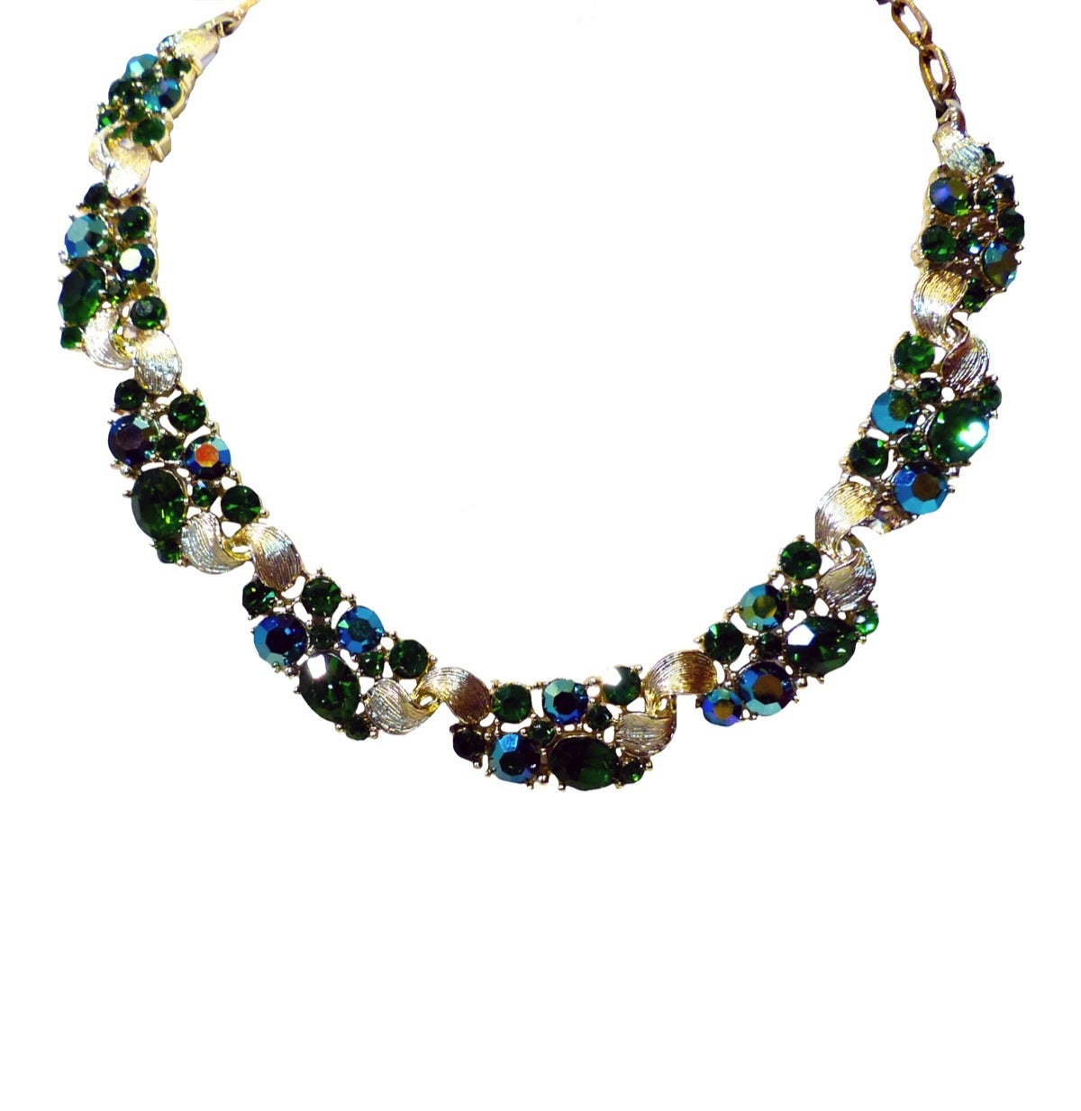 This Lisner set features faceted green & aurora borealis rhinestones in a gold-tone setting. The necklace measures 16 ½” long x 5/8” with a hook closure; the screw-on earrings are 7/8” x 5/8” and the bracelet is 6 ¾” x ½” with a pressure closure and