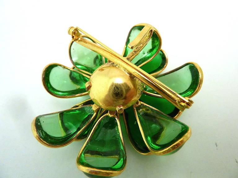 This vintage pin-pendant features a floral design in light and dark green Gripoix glass in a gold-tone setting. In excellent condition, this piece measures 2 ¼” in diameter and has both a turn pin and suspension hook.