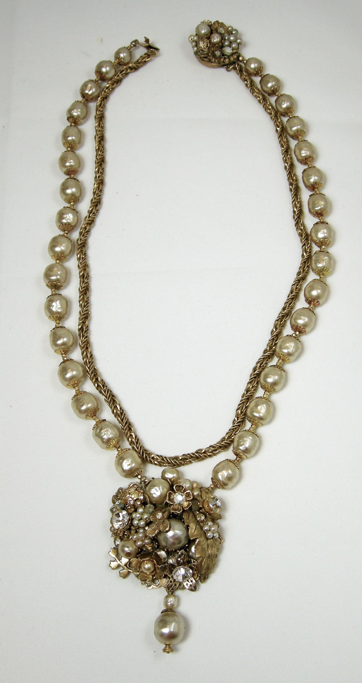 This is a vintage1960s two-strand Miriam Haskell necklace has a hanging centerpiece with pearl drop at the bottom. The inner strand has Haskell’s known chain and the second strand is a Haskell’s faux pearls strand with tiny gold nuggets between the