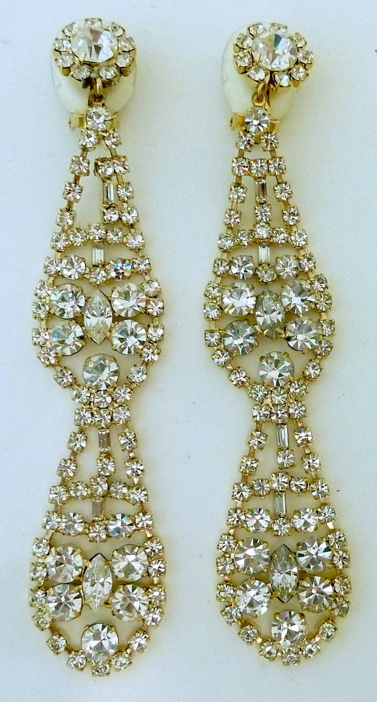 These long Kenneth Jay Lane clip-back earrings feature clear crystals in a gold-tone setting. You feel they are from the deco decade and they are very well made.    They’re in excellent condition and measure 4-5/8” x 1”. They are signed “Kenneth