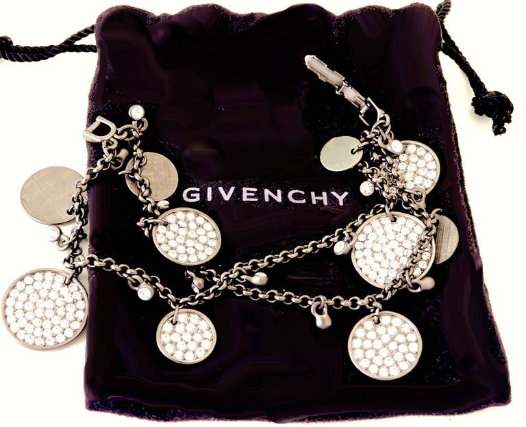 This vintage signed Givenchy bracelet features multiple discs, some with clear rhinestone accents, in an antiqued gold-tone setting.  This two strand bracelet measures 6 ½” with a fold-over closure and the largest disc is 5/8” in diameter.  In