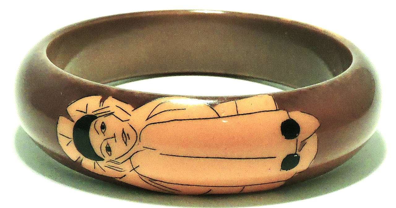 This is the famous 1940’s Bakelite bangle with two Harlequins in butterscotch  on a brownish Bakelite finish.  This bangle bracelet measures 8” x ¾” and is in excellent condition.