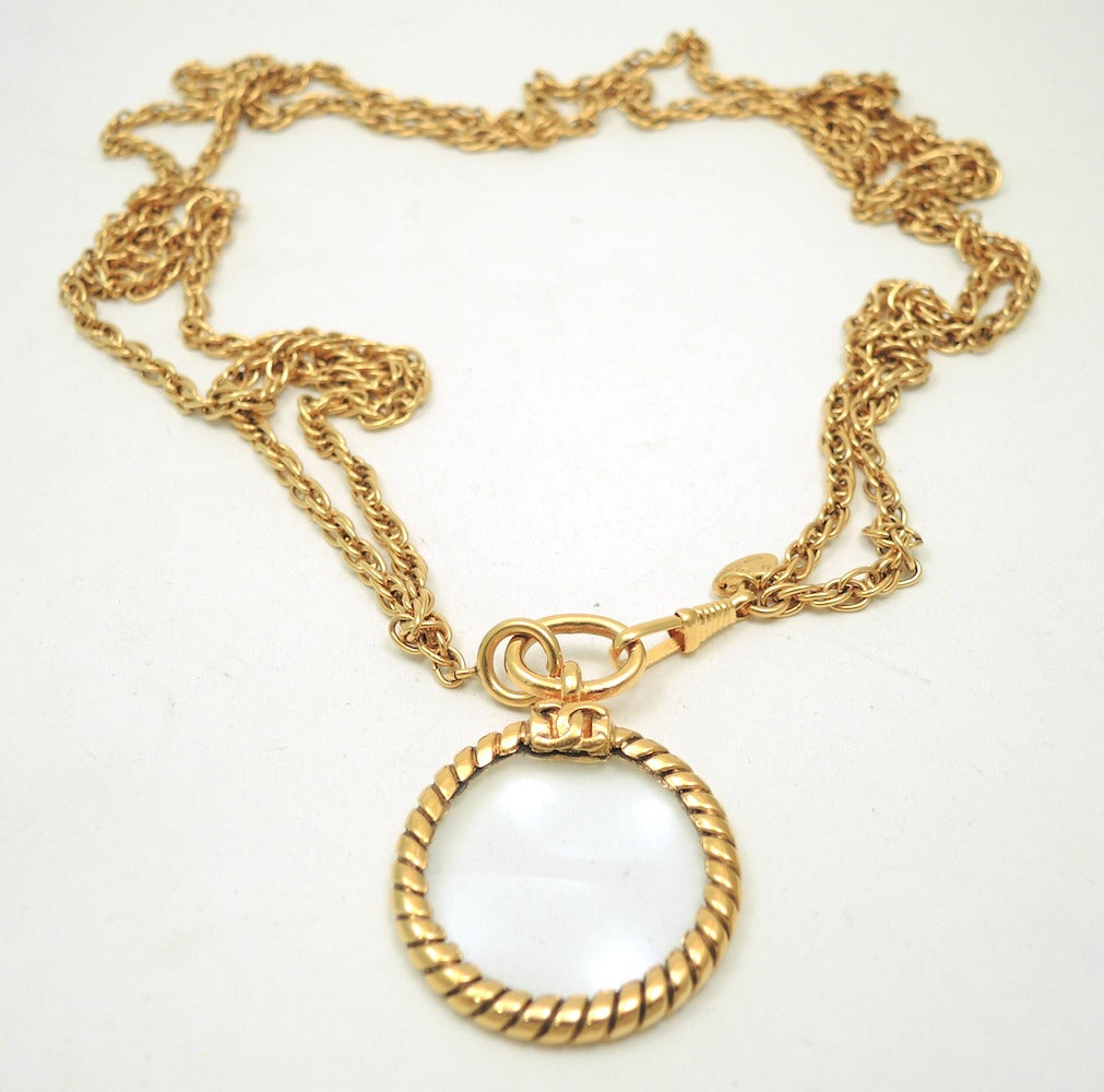 This vintage signed Chanel necklace features a magnifying glass pendant on a double link chain in a gold-tone setting. The pendant measures 2 ¼” x 1 5/8” and the necklace is 32” with a spring closure. In excellent condition, this pendant necklace is