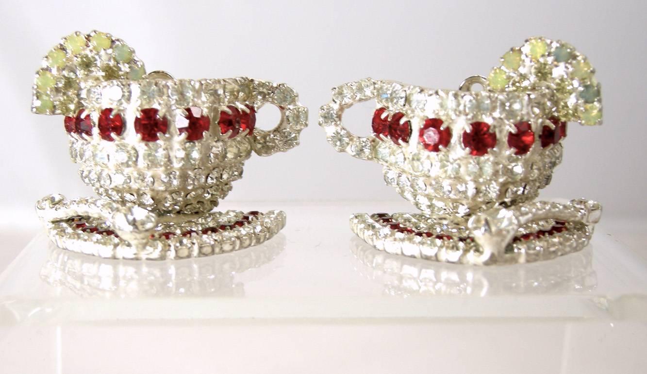 Dorothy Bauer is famous for her whimsical designs and these earrings are a perfect example featuring a ea cup and saucer with red and clear rhinestone accents in a silver-tone setting.  These clip earrings measure 1-1/4” x 1” are signed “Bauer” and