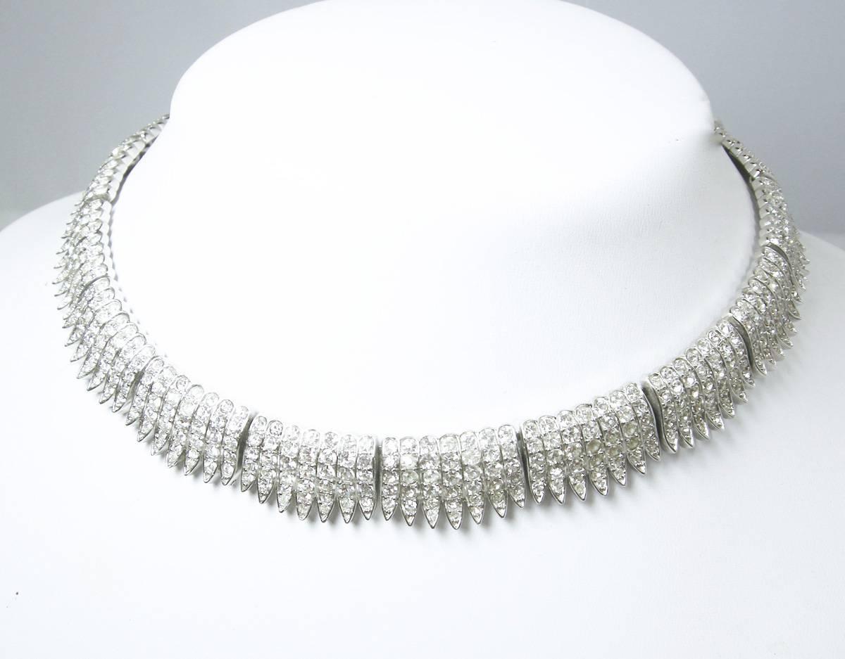 This vintage signed Trifari necklace looks so real … you can wear it and everyone will think it’s real. It features clear rhinestones in a silver-tone metal setting.  This necklace measures 16-1/2” x 5/8” with a hook closure and is signed “Trifari”.