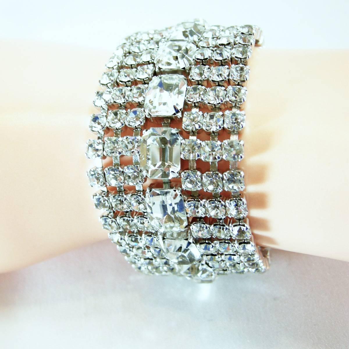 This striking signed Weiss bracelet features faceted clear rhinestones in a silver-tone metal setting. This bracelet measures 7” x 1-1/2” with a slide-in clasp and safety chain. It is signed “Weiss” and is in excellent condition.
