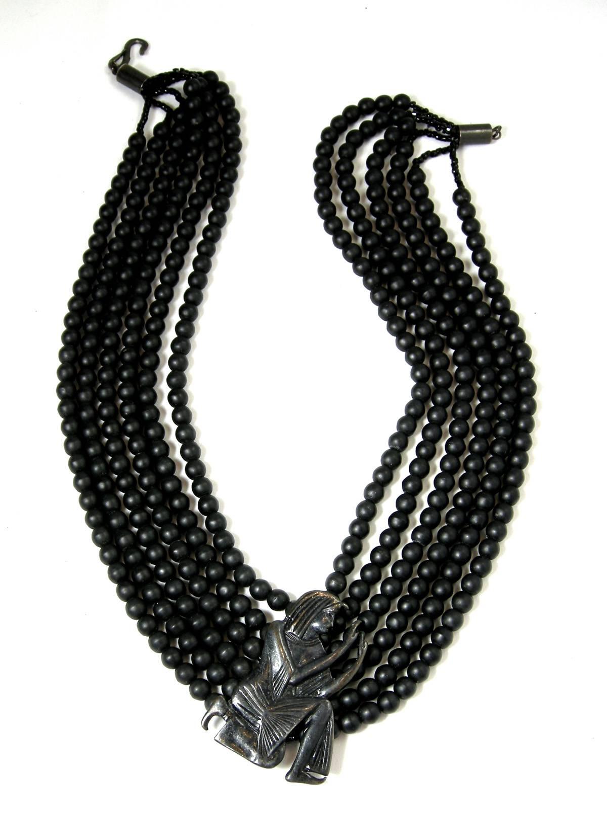 This vintage signed Hattie Carnegie necklace features 12 strands of black beads with an ornate Egyptian style centerpiece. This necklace measures 19-1/2” with a hook closure and the centerpiece is 2” x 1-1/2” and is signed “Hattie Carnegie”.  It’s