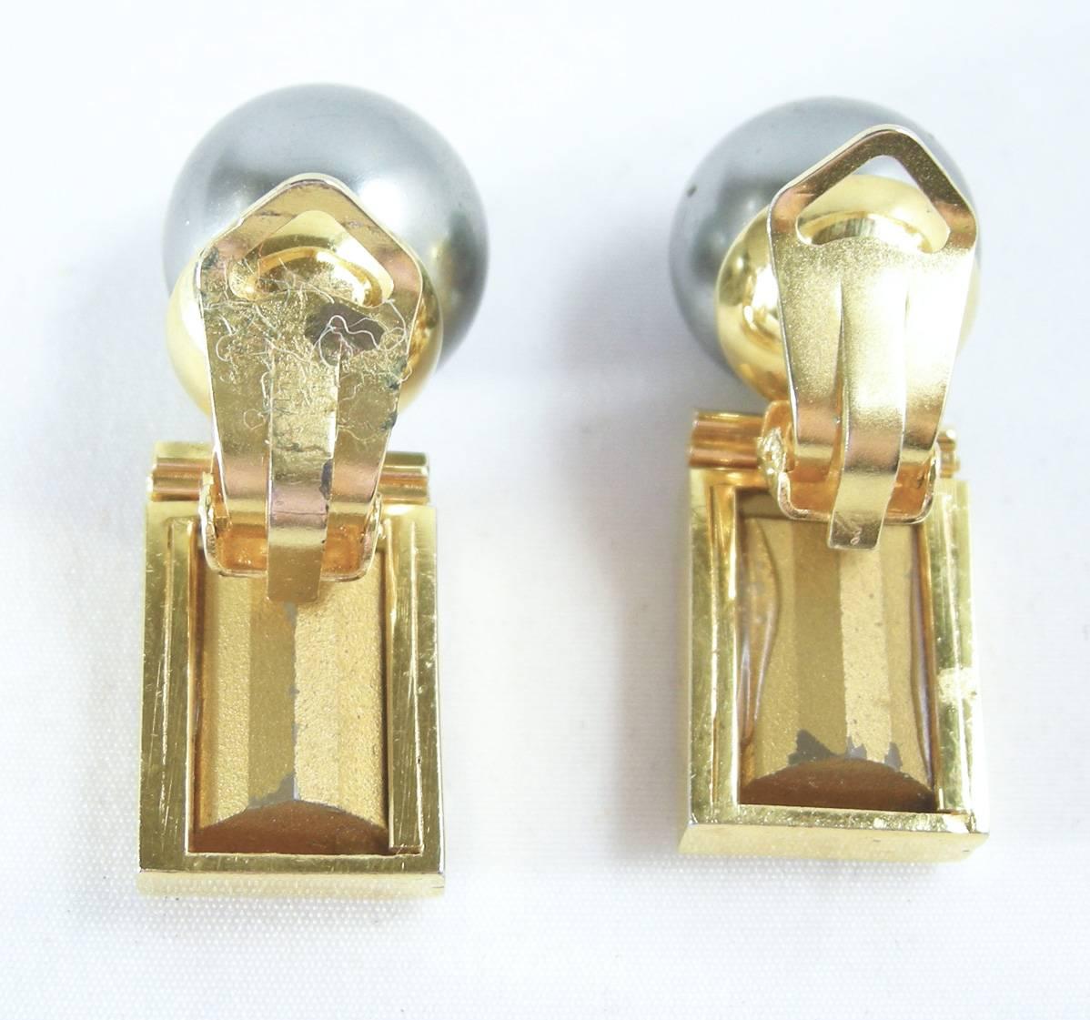 I like unusual earrings that I have not seen before.  These elegant vintage 1960s clip earrings feature gray faux pearls on the top with large bezel cut clear rectangle rhinestones on the bottom. It’s in a gold-tone setting and measure 1-1/2” x 1/2”