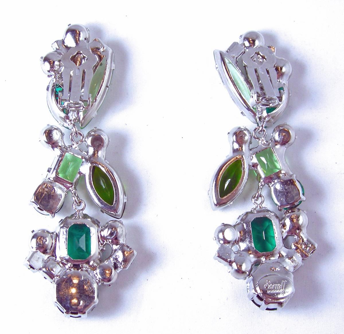 These gorgeous one-of-a-kind earrings by Robert Sorrell feature hues of green and clear faceted crystals in a silver-tone setting. These clip earrings measure 3” x 1” and are signed “Sorrell Originals”.  These earrings are in excellent condition.