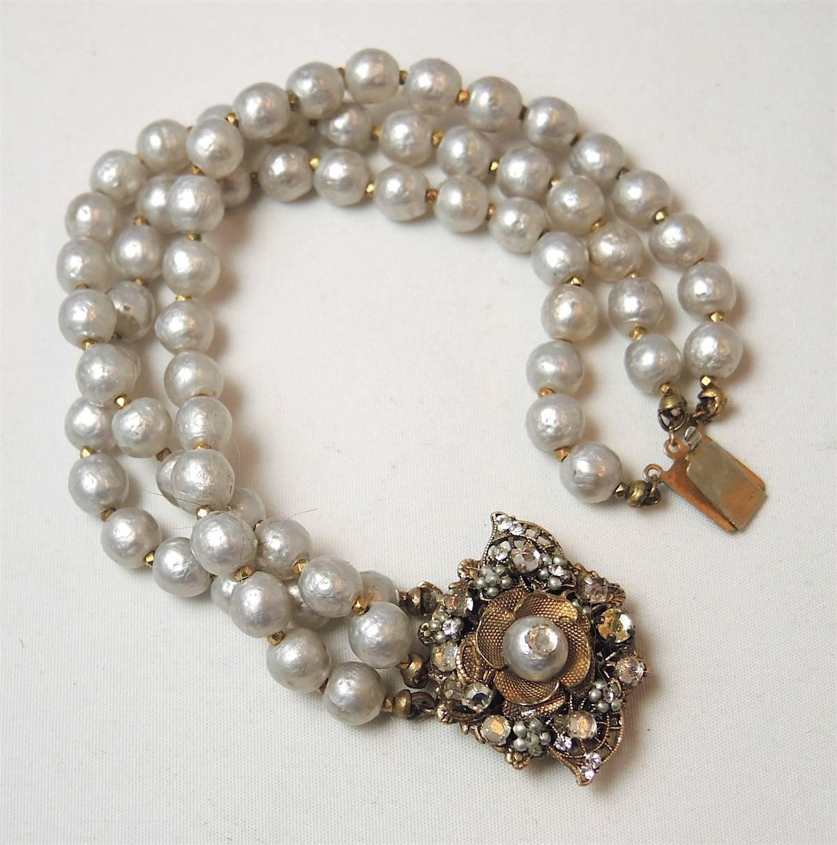 This is a beautiful, classic Miriam Haskell bracelet featuring 3 luscious strands of the famous Haskell faux pearls with faceted crystal accents in a gold-tone setting.  This bracelet measures 7” long with a 1” centerpiece/closure; each faux pearl
