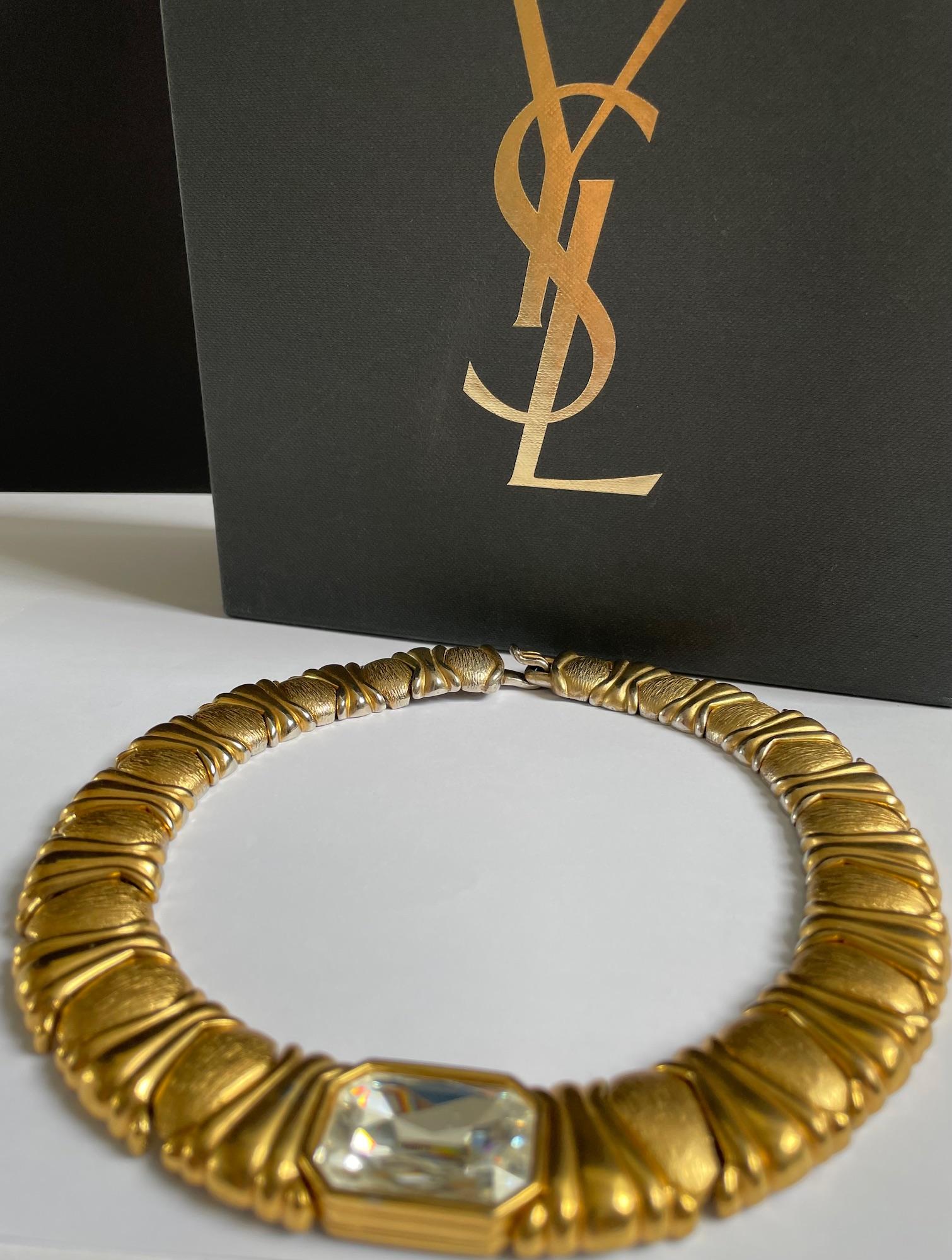 Vintage YVES SAINT LAURENT Haute Couture By CAILLOL Gold Plated Textured Emerald Crystal Necklace 1980s.

A rare vintage 1980s statement YVES SAINT LAURENT Haute Couture necklace by CAILLOL in gilt metal textured fitted collar ornamented with a