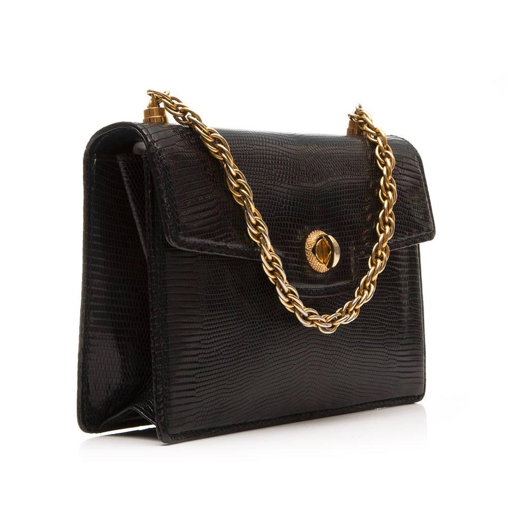 Gucci vintage handbag in black lizard skin featuring a twist lock detail and gold- tone chain. The interior of the bag is lined in black leather and boasts two open pockets and one zipped pocket. This bag can be carried in hand or over the
