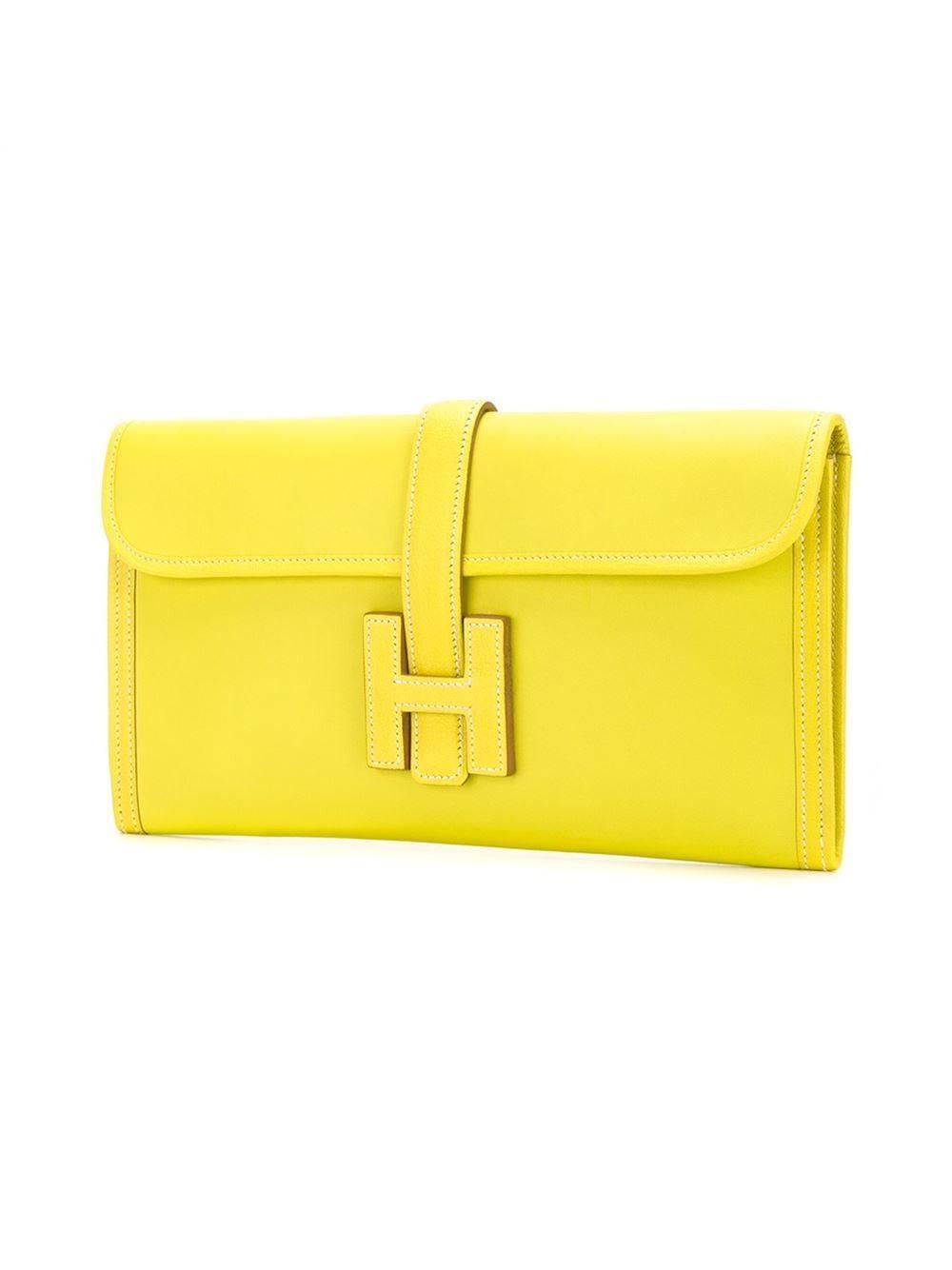 Yellow Swift leather embossed logo clutch from Hermès featuring a rectangular body, a stitch detail, a foldover top, a strap closure and a main internal compartment. 

Colour: Yellow (Sulphur)

Material: Swift Leather

Measurements: W: 29cm