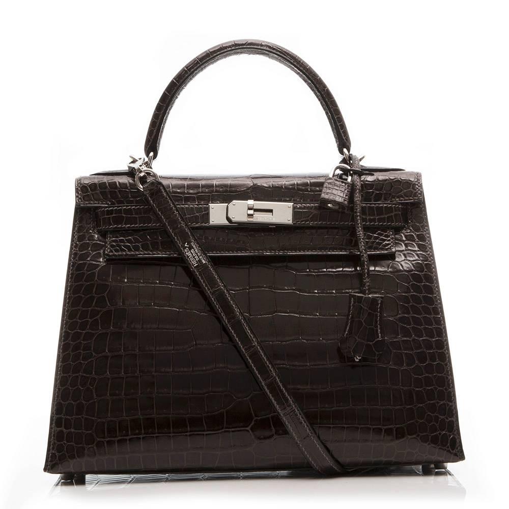 Hermes 28cm Kelly crafted in dark brown Cocaon Porosus crocodile leather, featuring palladium hardware. The interior of the bag is lined in matching goat skin leather and has two open pockets and one zipped pocket.

Stamp: K (2007)

This bag