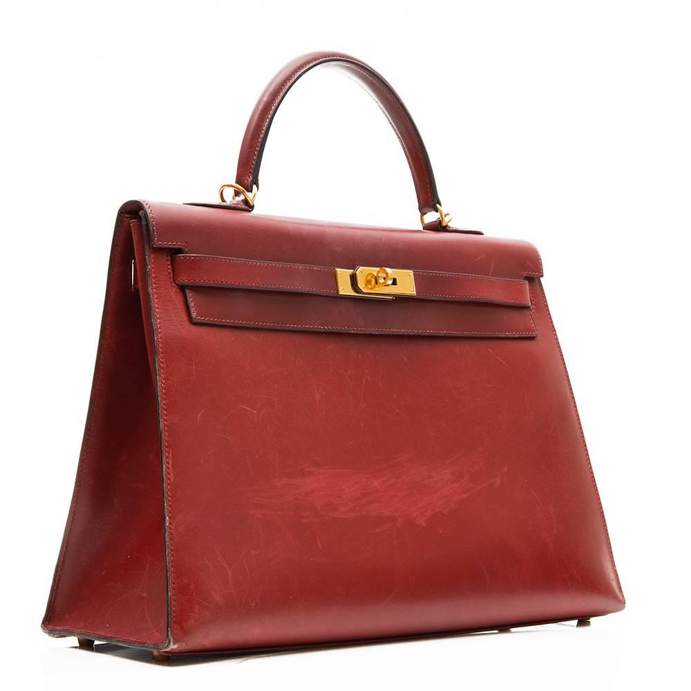 Hermes Kelly 35cm Kelly bag in burgundy box calf leather featuring gold- plated hardware. The interior of the bag is lined in matching goatskin leather and has one zipped pocket and two open pockets.
This bag comes with its original strap and lock