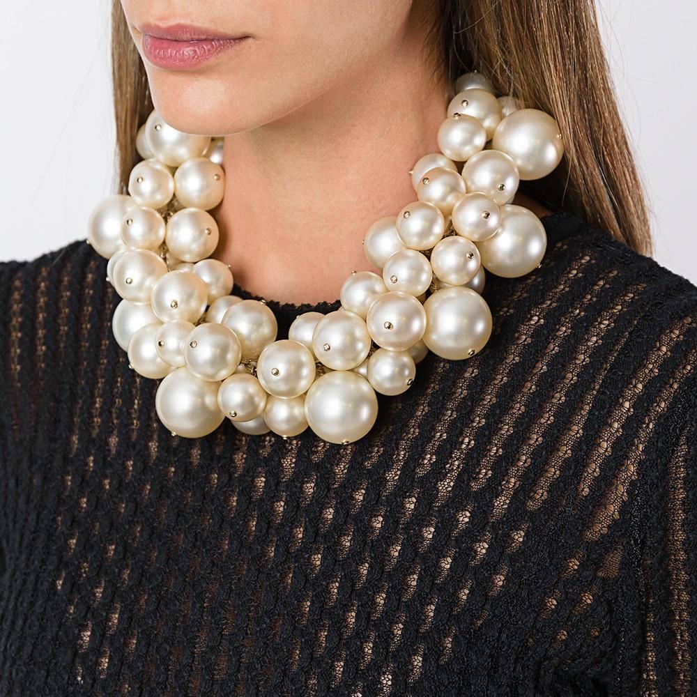 Evoke decadence with a statement necklace from Chanel, crafted from large bourgeois pearls that cluster across the neckline, offset by pale gold-tone accents. It is finished with a large, hanging Chanel monogram charm at the nape of the neck.