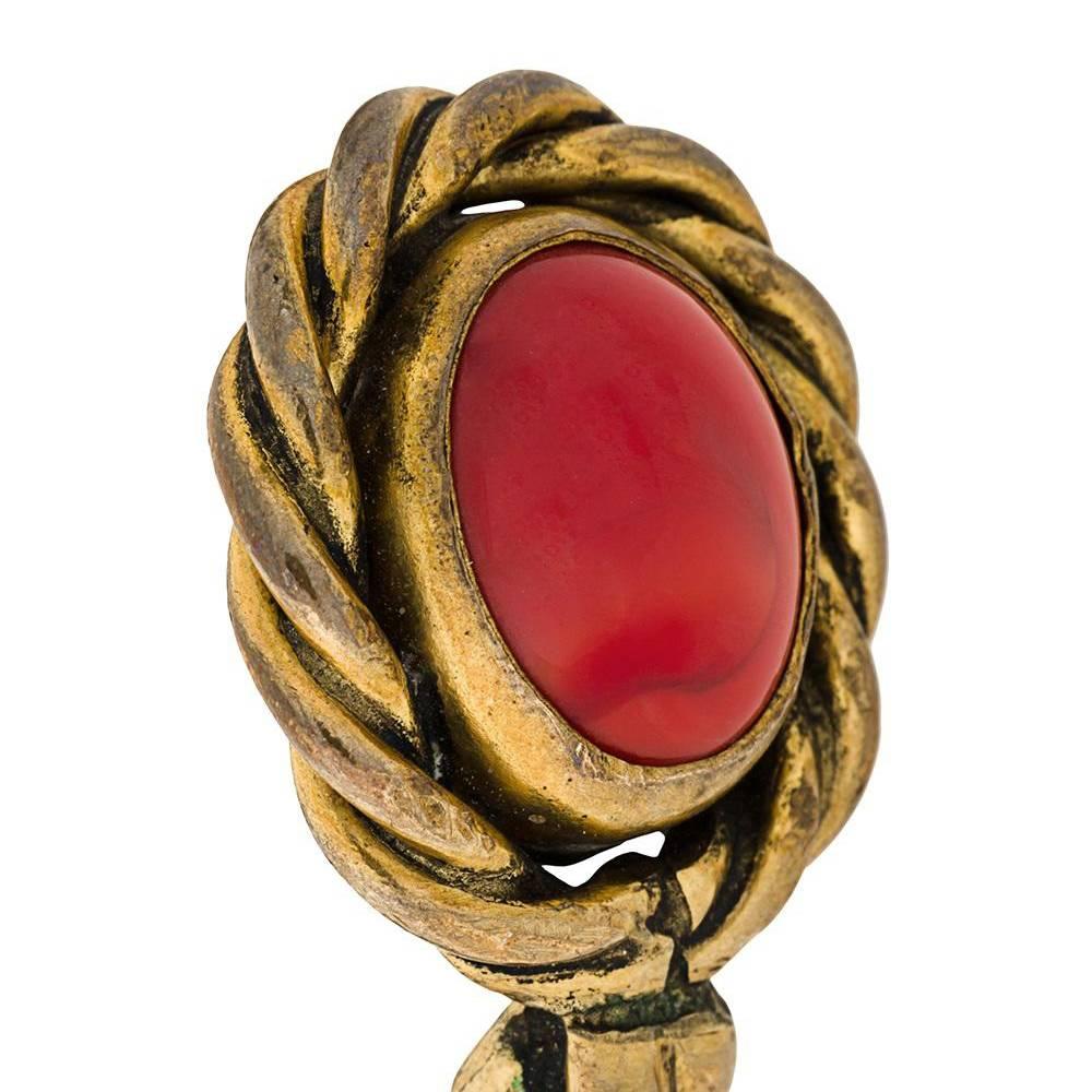 This vintage cuff by Chanel is formed of elegantly entwined gold-gilded strands offset with two red cabochon stones. This Chanel cuff was designed in 1984, one year after Karl Lagerfeld was inducted to the helm of the maison.

Please note this
