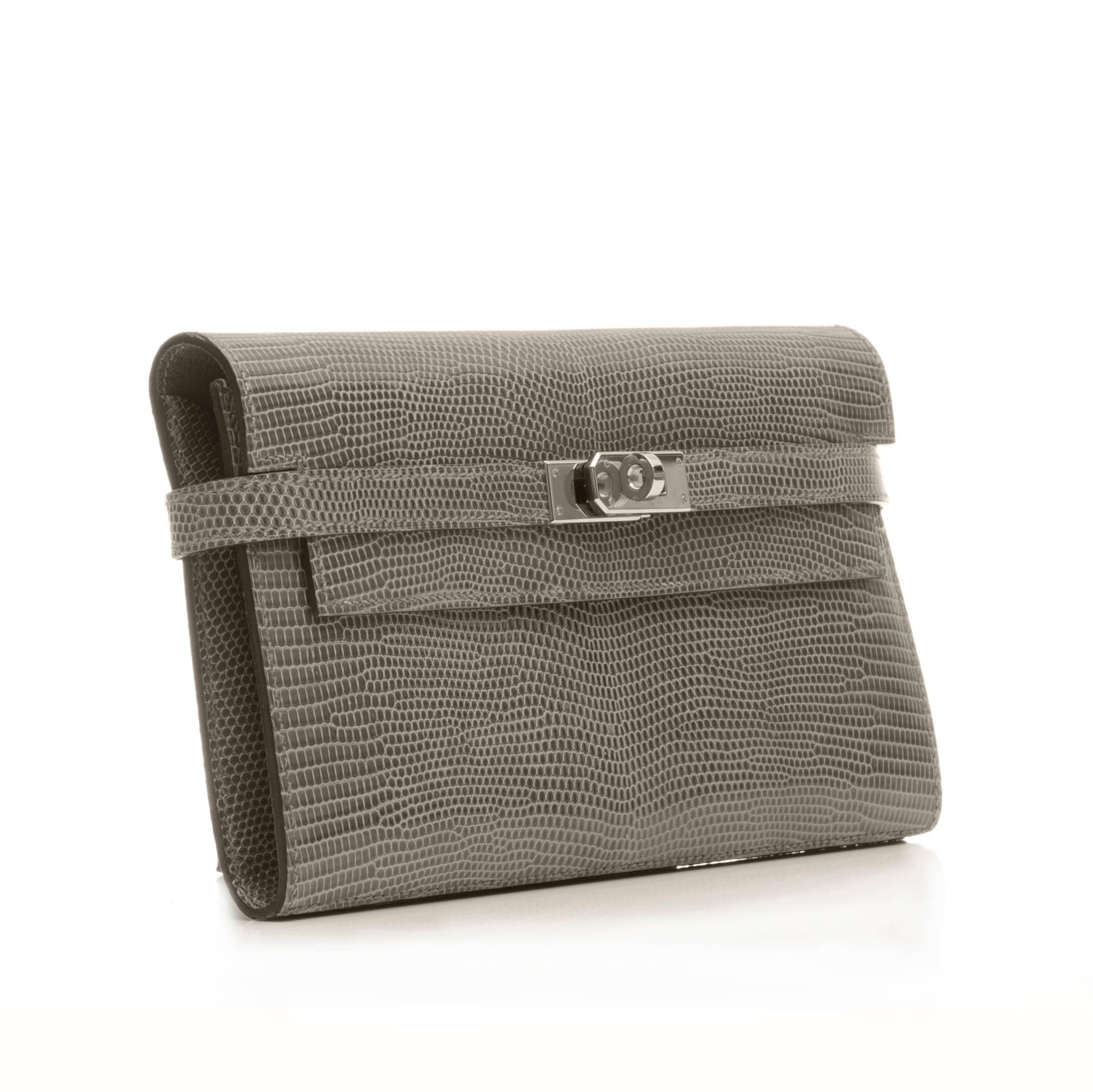 Crafted in a Gris Foncé lizard skin and offset with a palladium turnlock closure, this Hermès Kelly wallet features the iconic motifs of the Hermès Kelly handbag along its slim silhouette. Its interior contains multiple slip pockets and a zipped