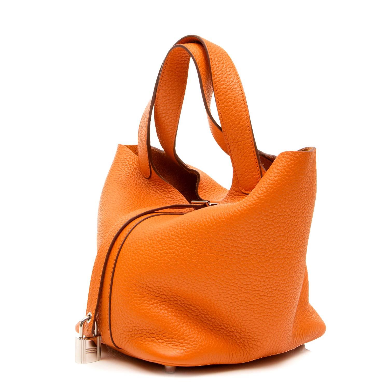 Obtain the effortless appeal of the Hermès Picotin handbag. This petite model features a highly grained Clemence leather in the brand’s iconic Orange hue. Finished with palladium hardware, the design features a buckle closure at its top, a padlock,