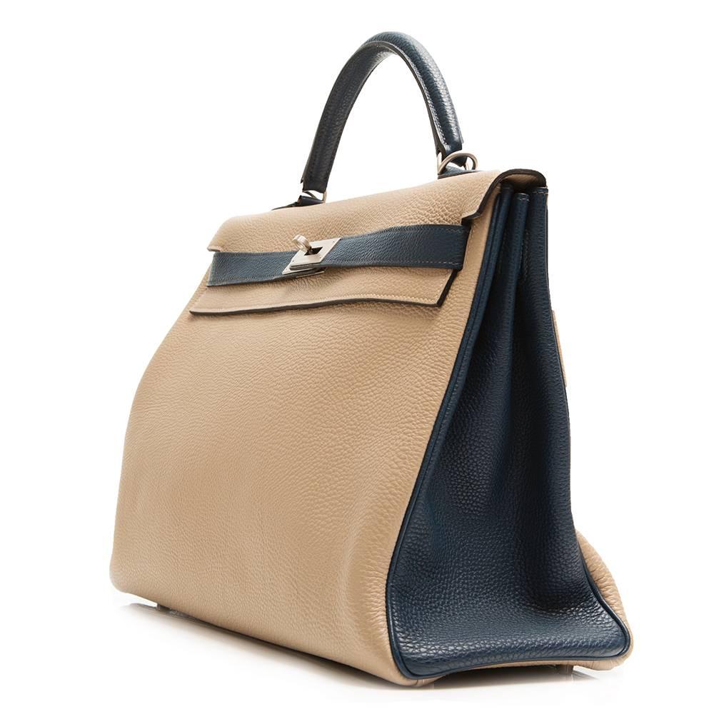 This Hermès Kelly 40 bag is rendered in an elegant bi-tone that complements its ladlylike silhouette. An Etoupe body – a grey-toned beige – is offset with Blue de Galice handles, belt arms and piping. It is crafted in Togo leather, a popular