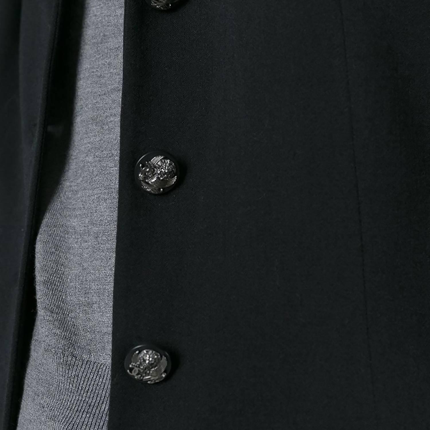 This vintage black Chanel jacket is a perfect instance of Chanel's deft tailoring, cut to a slightly cinched waist and a sharp shoulder profile. Accented with a silver-tone chain trimming the lining, and black and gunmetal buttons embossed with a