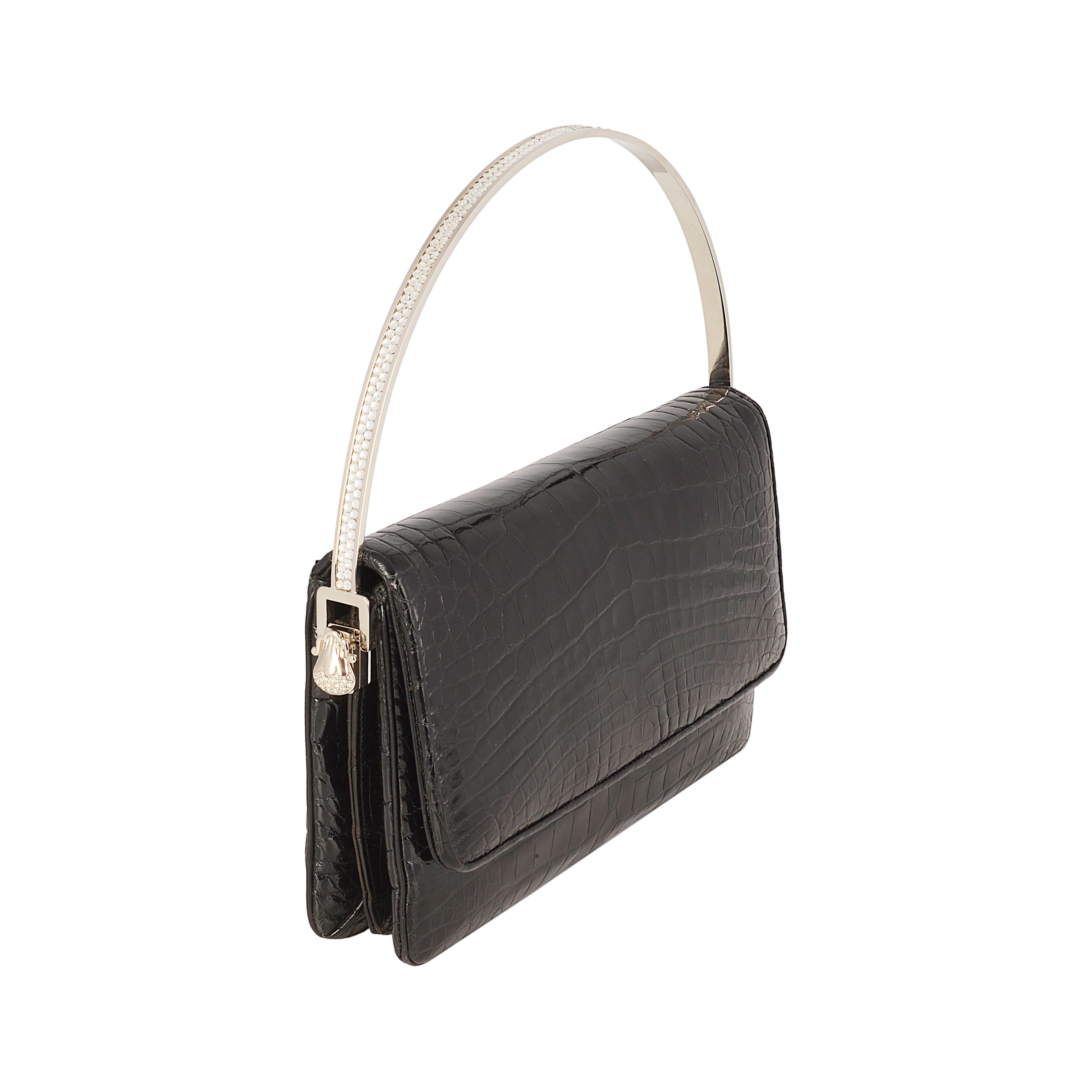 This exceptional Judith Lieber bag is crafted from black crocodile leather, and features a detachable handle adorned with Lieber's signature crystals. This can be swapped for a long silver chain strap to transform this versatile clutch into a