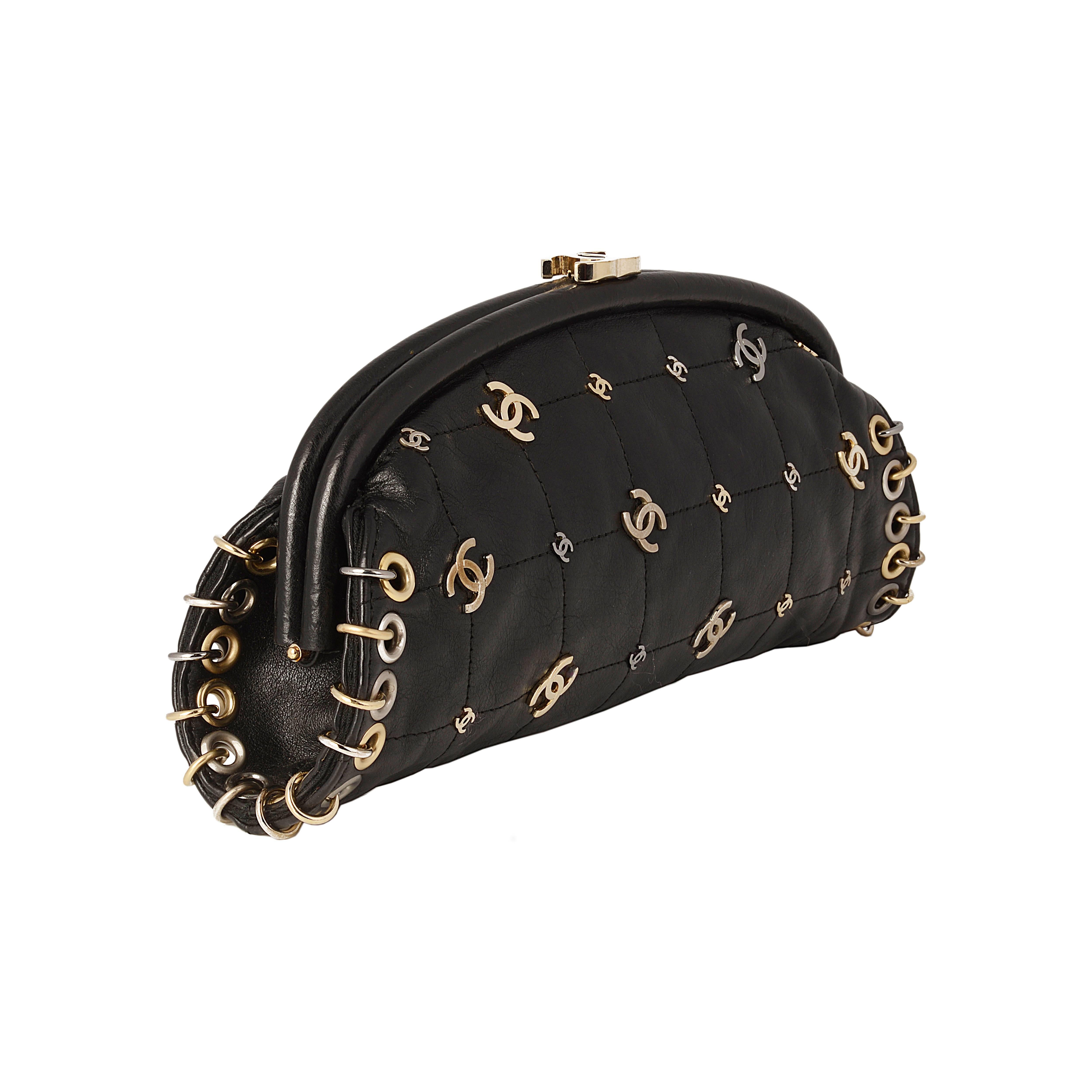 This unique Chanel pochette is crafted from black leather, featuring an internal zipped pocket. The exterior is adorned with the iconic interlocking 'CC' logo and edged with gold rings. This clutch bag is finished with a logo clip locking