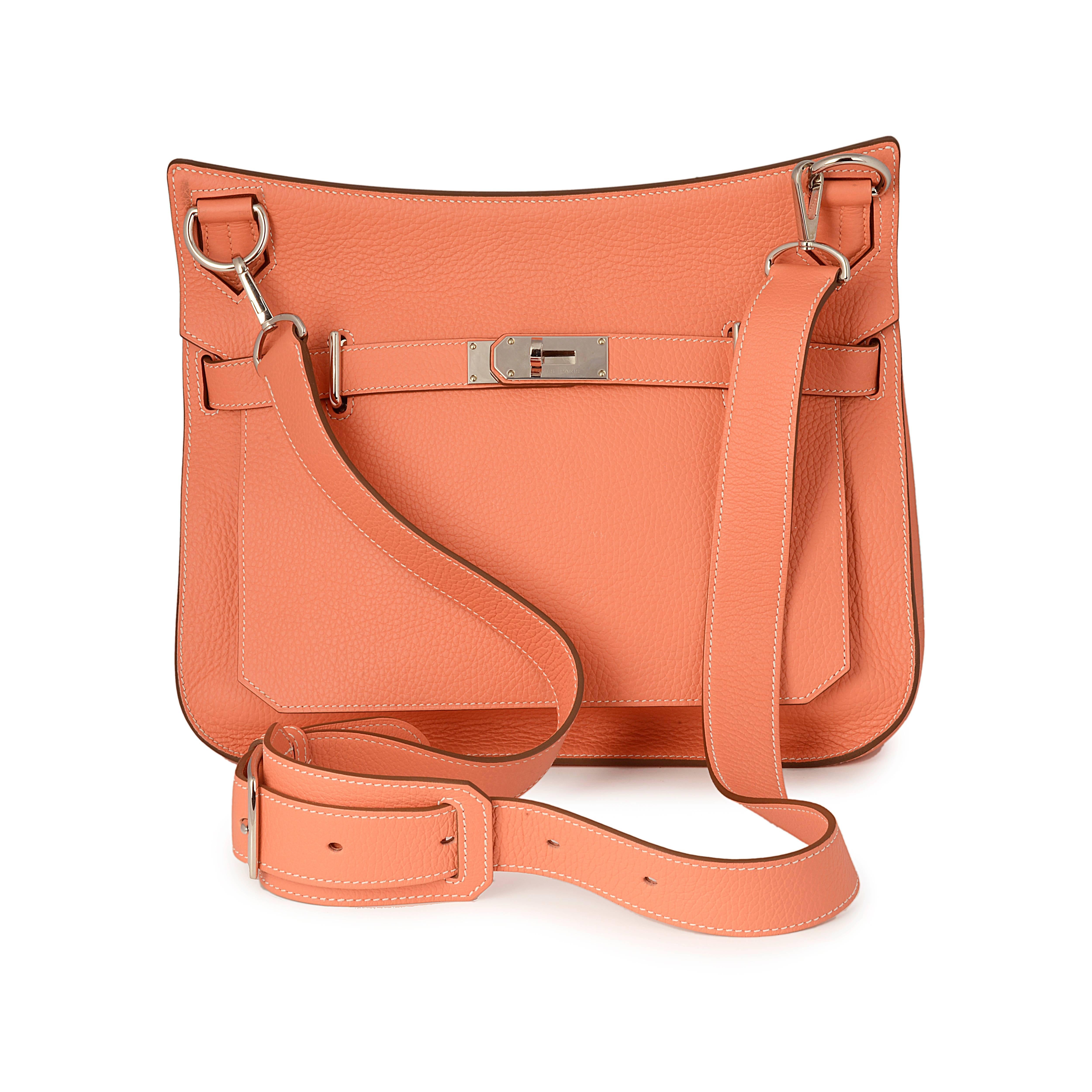 This luxurious Hermes messenger bag is crafted from Clemence leather featuring a front flap closure with the iconic Hermes turn-lock clasp closure and palladium hardware accents. This opens to a roomy coral leather-lined interior with front zip