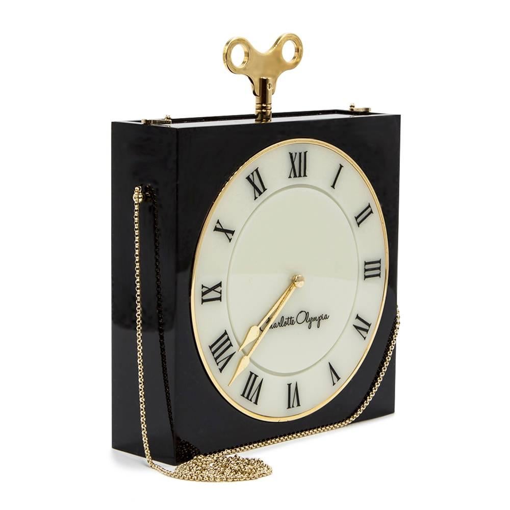 This highly sort after Charlotte Olympia Timepiece clutch is an engraved perspex matchbox clutch with a box chain shoulder strap. The bag has a functioning Roman numeral time clock on the front.

Colour: Black and white with gold toned