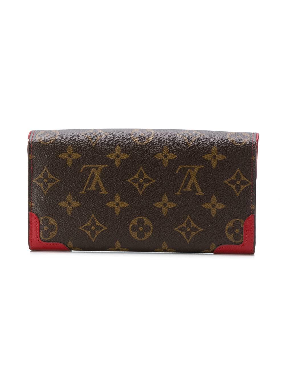 This brown and red leather monogram wallet from Louis Vuitton Vintage features a foldover top with snap closure, a main internal compartment, an internal slip pocket, a coin pocket, multiple card slots, a monogram pattern and gold-tone