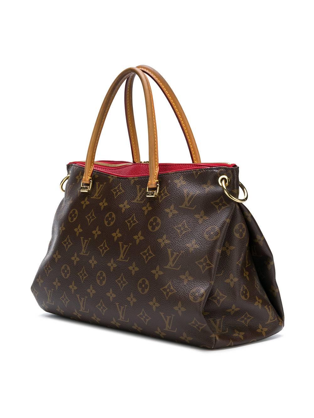 This brown, beige and red leather monogram oversized tote from Louis Vuitton Vintage featuring a round top handle, a main internal compartment, an internal logo patch, an internal slip pocket, a monogram pattern, gold-tone hardware, hanging padlock