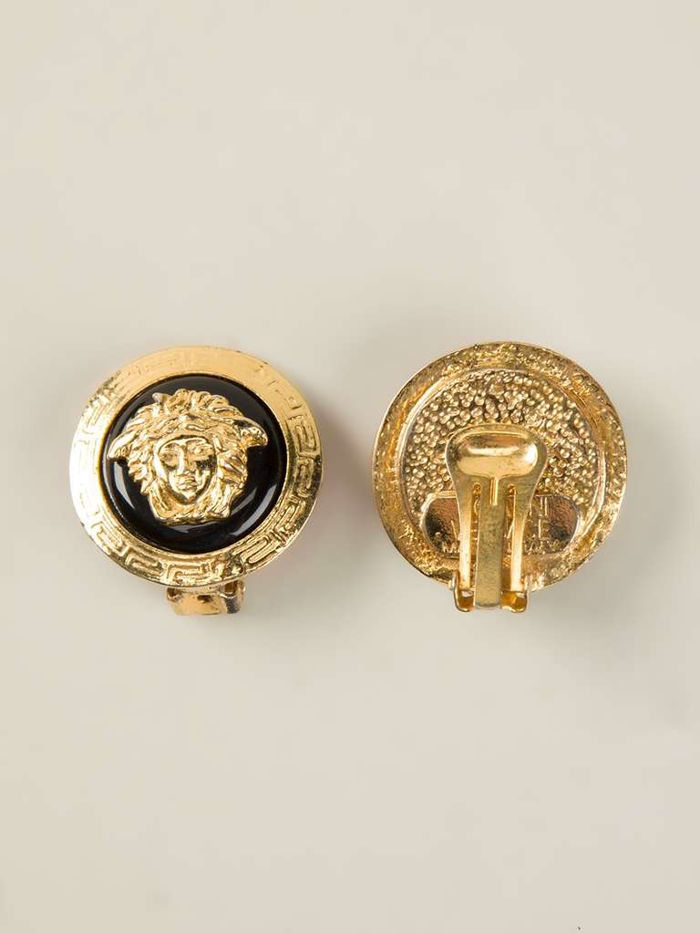 Gold plated Medusa clip-on earrings from Gianni Versace Vintage in a round shape and featuring the popular Medusa logo over a contrast black background.