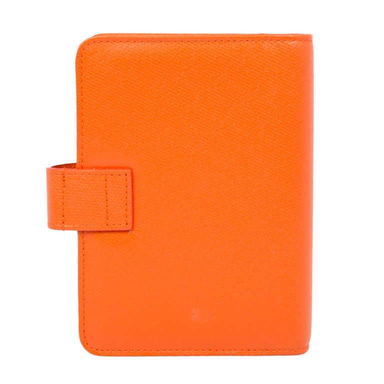 Pocket Filofax by Chanel, crafted in orange leather and boasting a press-stud closure with orange and gold CC logo button. Its interior has a refillable Filofax featuring a diary and address book plus three pockets: two on the front cover and one on