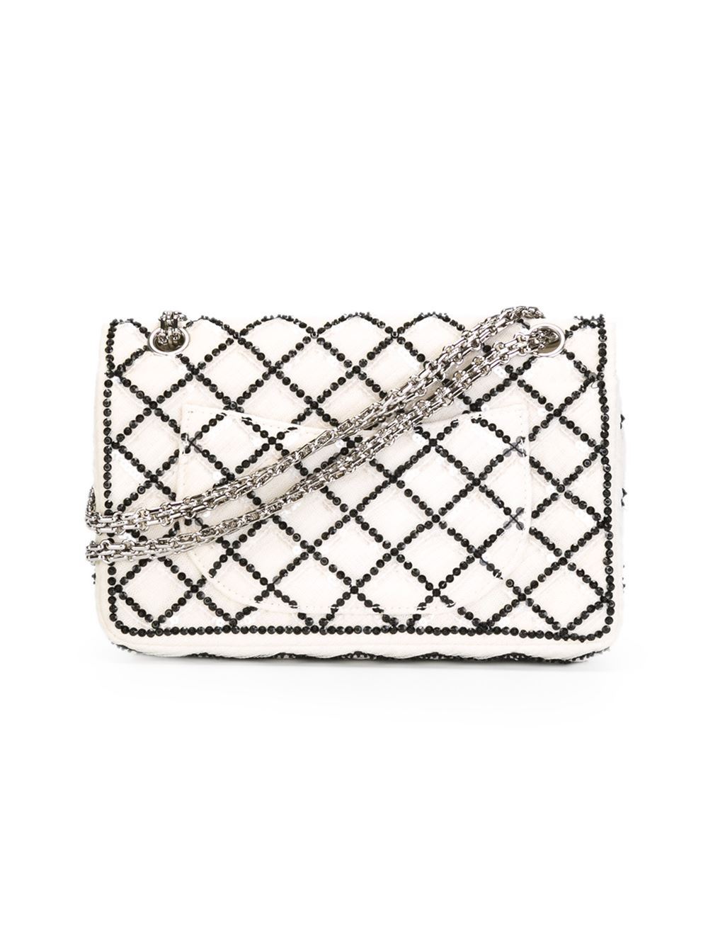 This white and black cotton sequined flap shoulder bag from Chanel features a foldover top with twist-lock closure, a quilted effect, a chain shoulder strap, a back slip pocket, an internal logo patch, multiple interior compartments, an internal