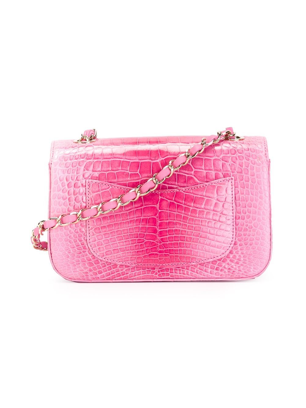 This pink crocodile leather embossed flap crossbody bag from Chanel features a fold-over top with twist-lock closure, a gold-tone logo plaque, a chain and leather strap, a back slip pocket, an internal zipped pocket, an internal slip pocket and an