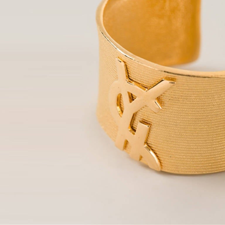 Yves Saint Laurent Vintage Logo Cuff. Gold plated metal cuff from Yves Saint Laurent Vintage featuring carved logo at the front.

Colour: Gold

Material: Gold- plated metal
Measurements: width: 4 centimetres, circumference: 19