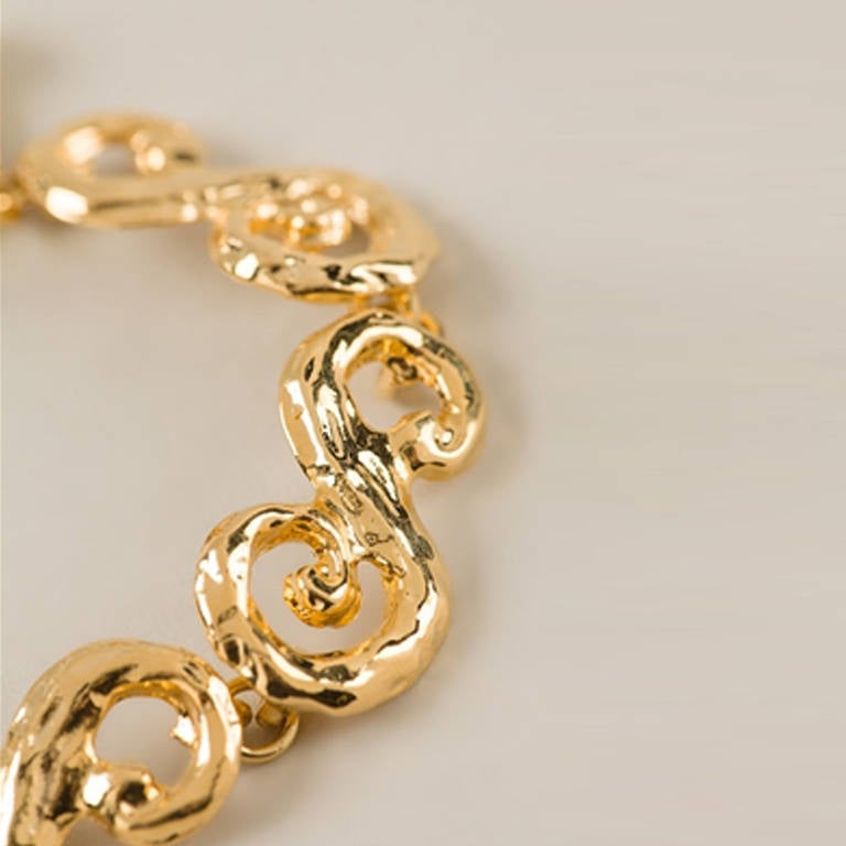 Yves Saint Laurent Swirl Chain Bracelet.  	
Carry a style staple when it comes to accessories: this Gold plated metal swirly chain bracelet from Yves Saint Laurent Vintage. Featuring a toggle fastening and a gold-tone branded logo plaque, this
