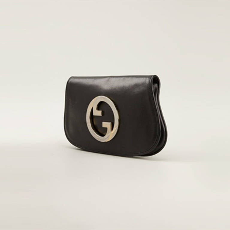Gucci Vintage Black Leather Logo Clutch.  	
Simplicity meets brand power in this black leather logo clutch from Gucci Vintage. Featuring a foldover top accented with a silver-tone logo plaque and magnetic closure, this elegant piece encapsulates