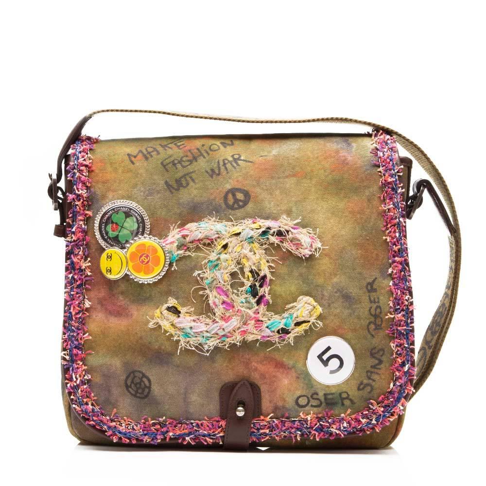 Green and multicoloured cotton distressed messenger bag featuring a foldover top, a strap closure, an adjustable shoulder strap, frayed edges, a distressed graffitied design and multicoloured pins.

Colour: Multicolour

Material: Leather 100% /