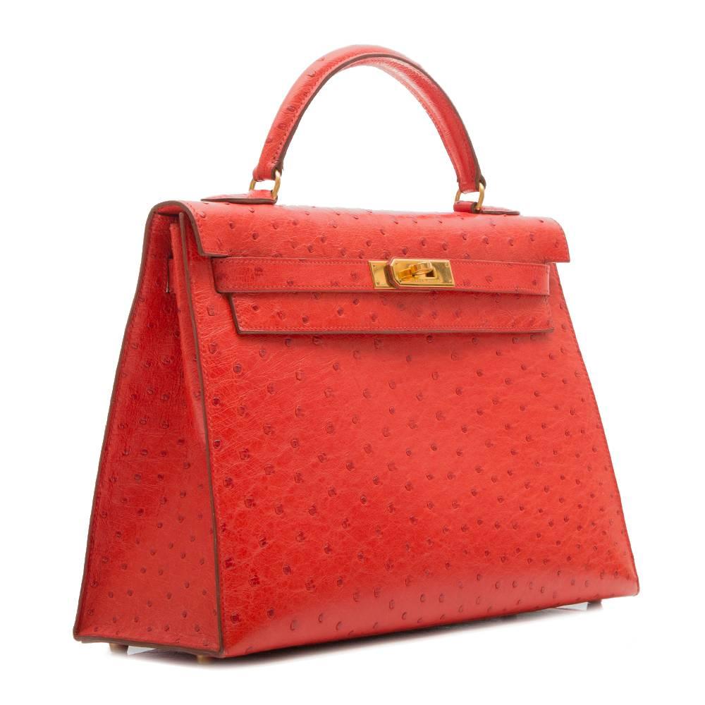 Hermès vintage ​Rouge Vif 32cm Kelly bag in ostrich leather featuring gold plated hardware. The interior of the bag is lined in matching goat leather with one zipped and two open pockets. 
This bag comes with its strap, lock and key, protective felt