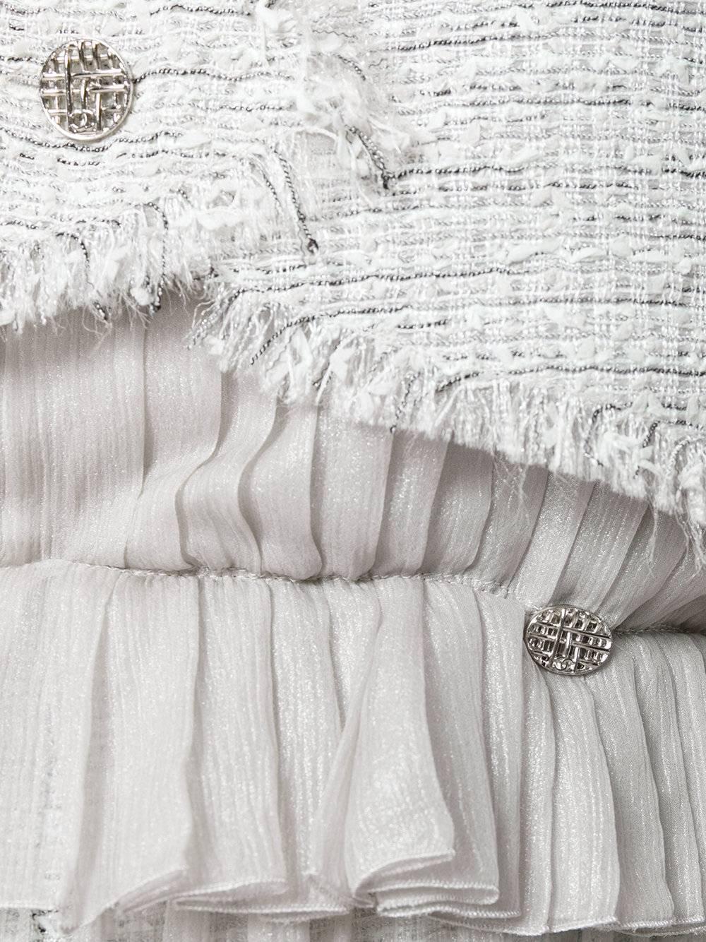 This vintage Chanel twinset includes a cropped tweed waistcoat and a midi dress. Its dress has a metallic tweed skirt, overlaid with floaty, crinkled chiffon that has a lustrous sheen. With a loose fit, it is pleated down the frame and frilled along