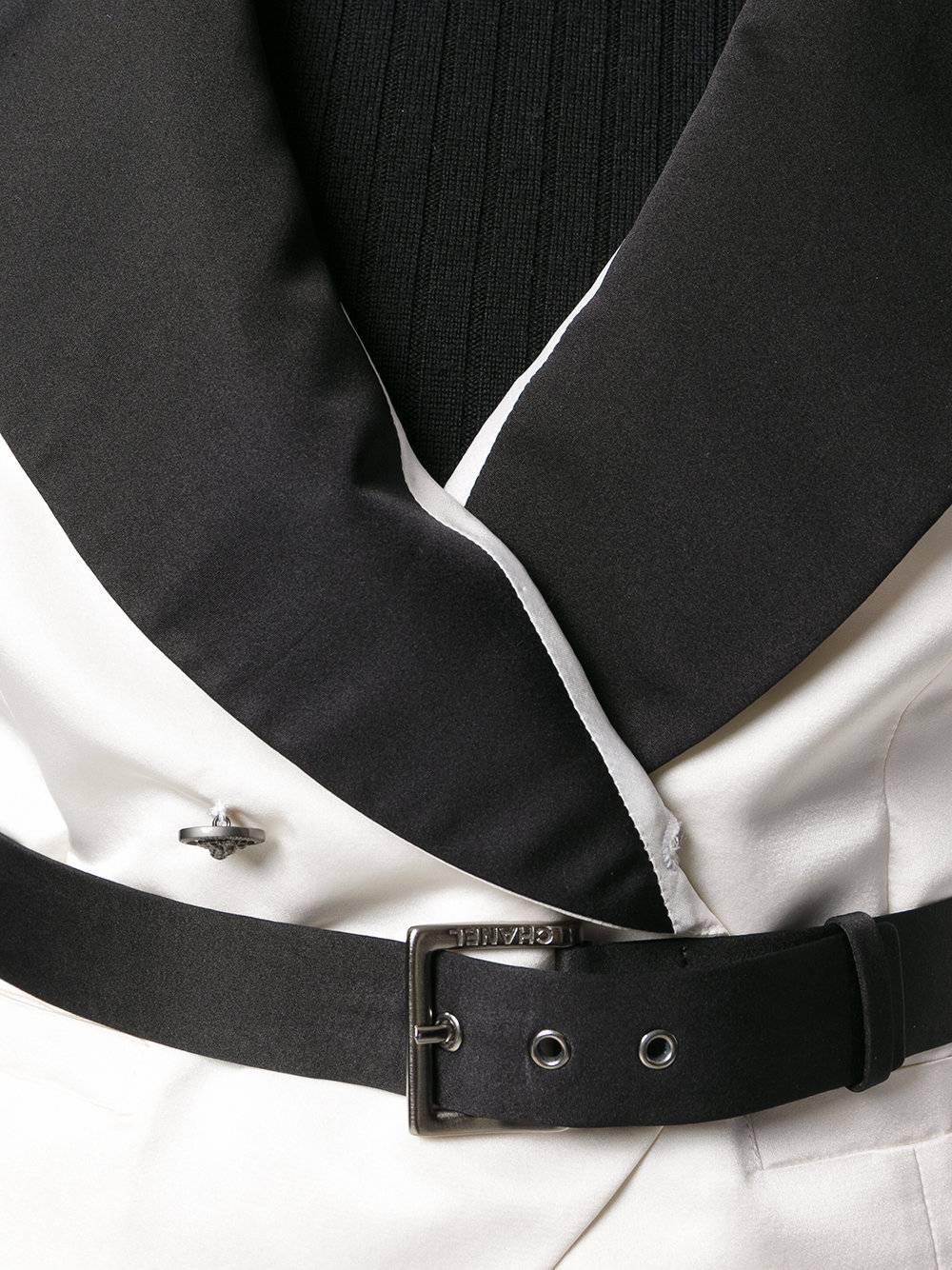 This waistcoat reflects Gabrielle Chanel's personal style, riffing on a men's waistcoat and deftly tailored in monochrome silk-satin. Its relaxed, double-breasted frame cinches with a black leather belt, with a buckle embossed with Chanel lettering.