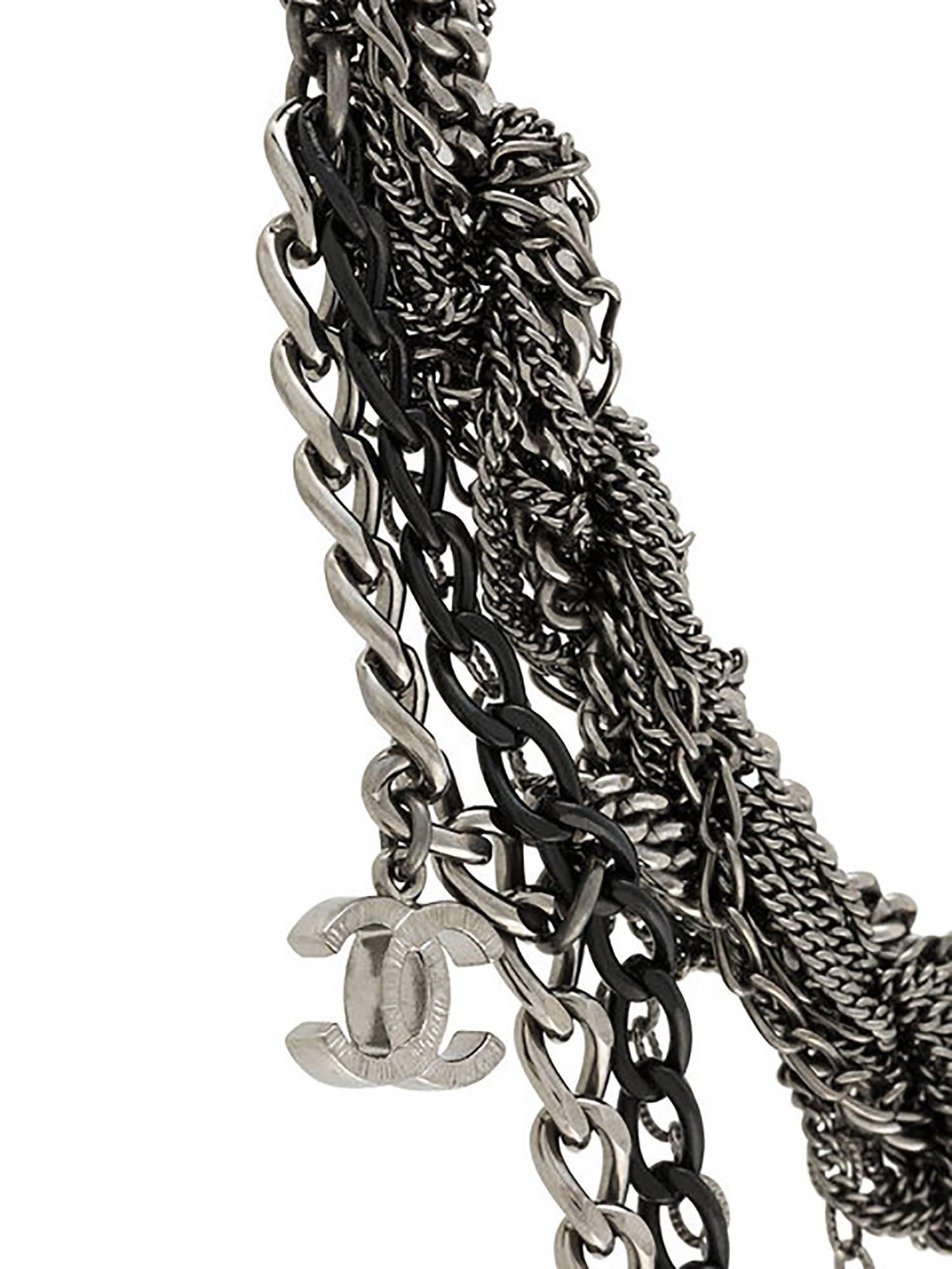 Capturing the dark glamour so often seen at Chanel, this necklace is crafted from ropes of gunmetal and black chain, finished with cascades of Chanel monogram charms. Sitting comfortably around the neck with a black fabric-covered elastic, the short